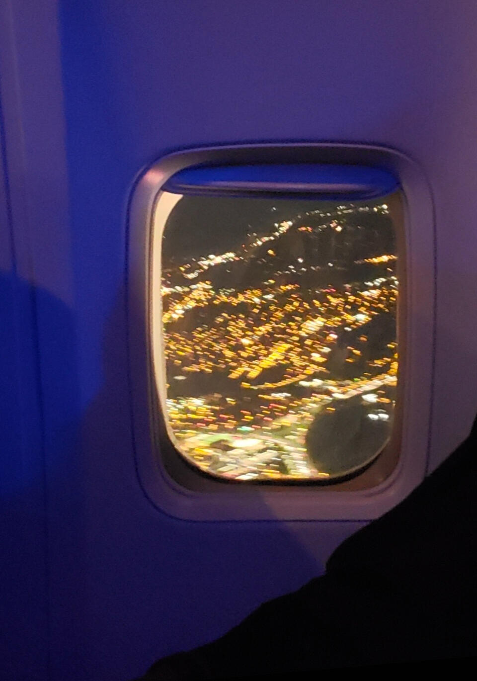 View from an airplane window overlooking a city at night, showcasing travel and commercial photography by LuxeGrid Media.